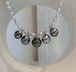 Side view of the white pearl strand and Tahitian drops on a jewelry display.