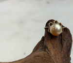Adjustable golden pearl ring combining rich tea-colored tones with a vintage-inspired floral lace setting.