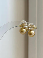 Elegant South Sea pearl earrings featuring deep tea golden pearls and a sparkling geometric silver setting.