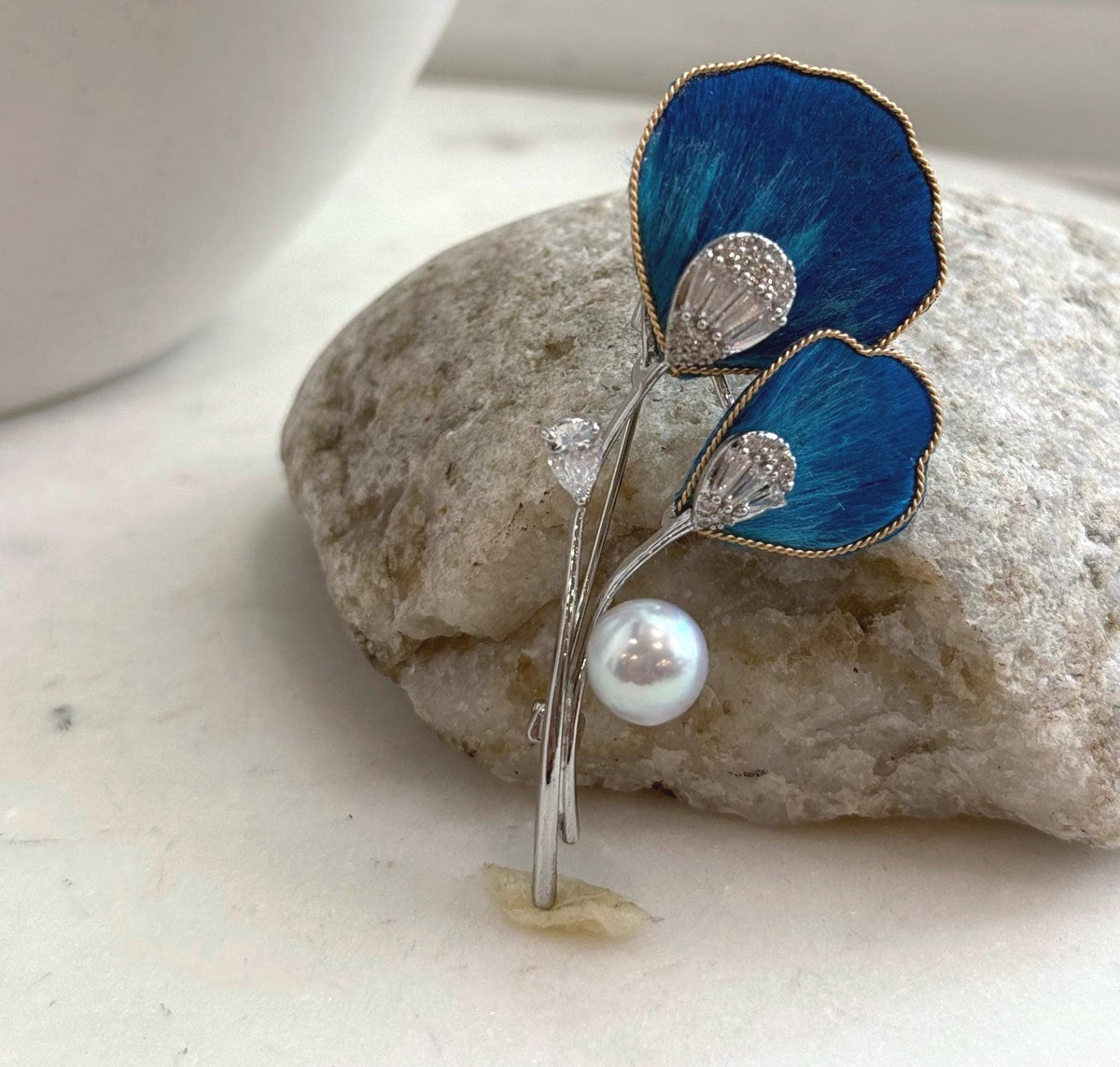 Blue floral brooch pendant with silver-tone stems and a dangling white pearl.