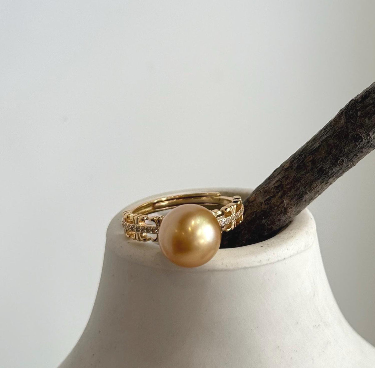 Detailed view of the layered band and small clear accents beside the pearl.