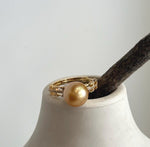 Detailed view of the layered band and small clear accents beside the pearl.