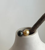 Close-up of two genuine saltwater pearls in contrasting golden and dark tones.