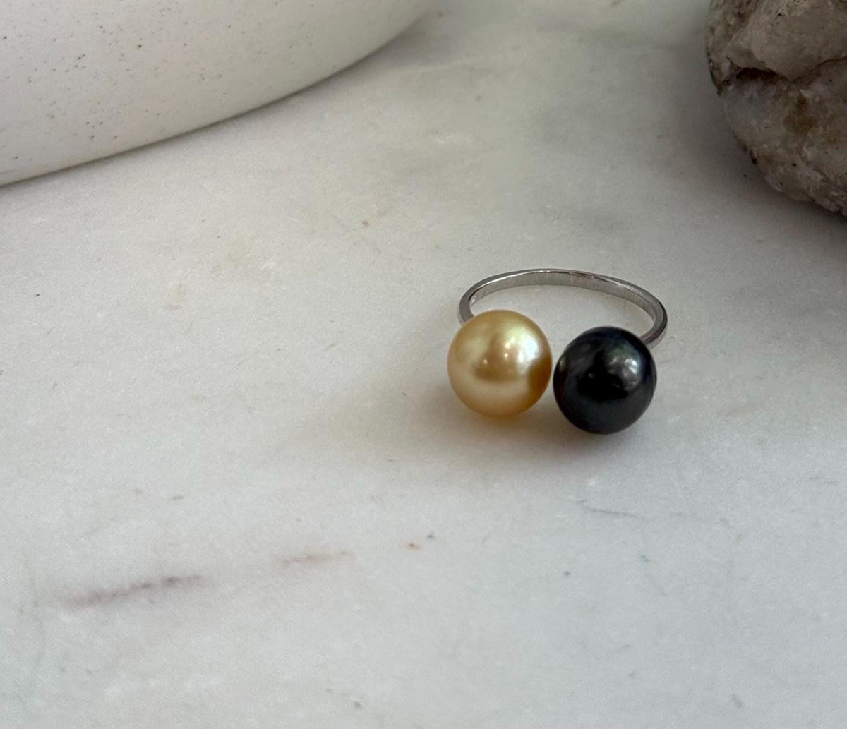 Elegant double pearl ring displayed beside a natural stone.