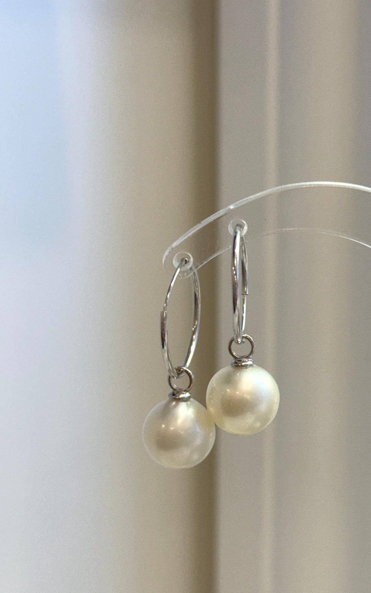 Pair of luminous white pearls suspended beneath slim silver hoops