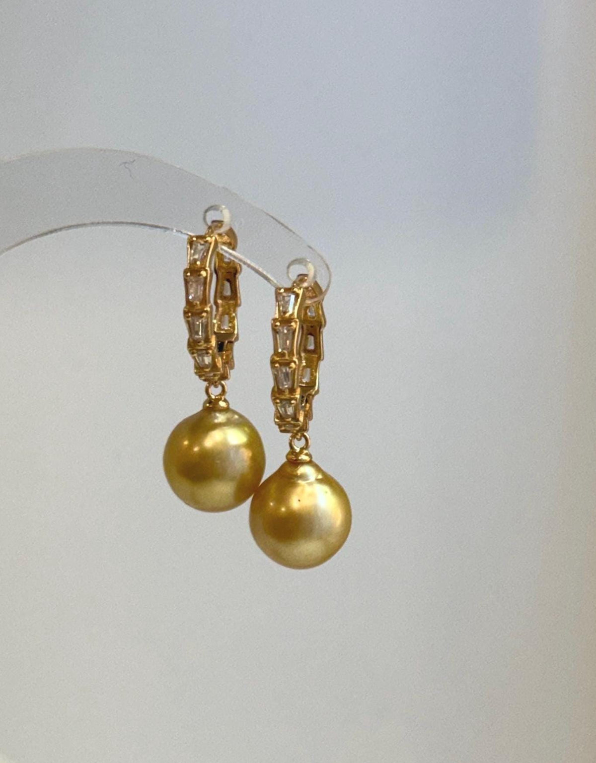 Close-up of lustrous golden South Sea pearls on elegant gold-tone hoop earrings.