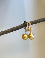 Crystal details add sparkle above the golden pearls on these statement hoop earrings.