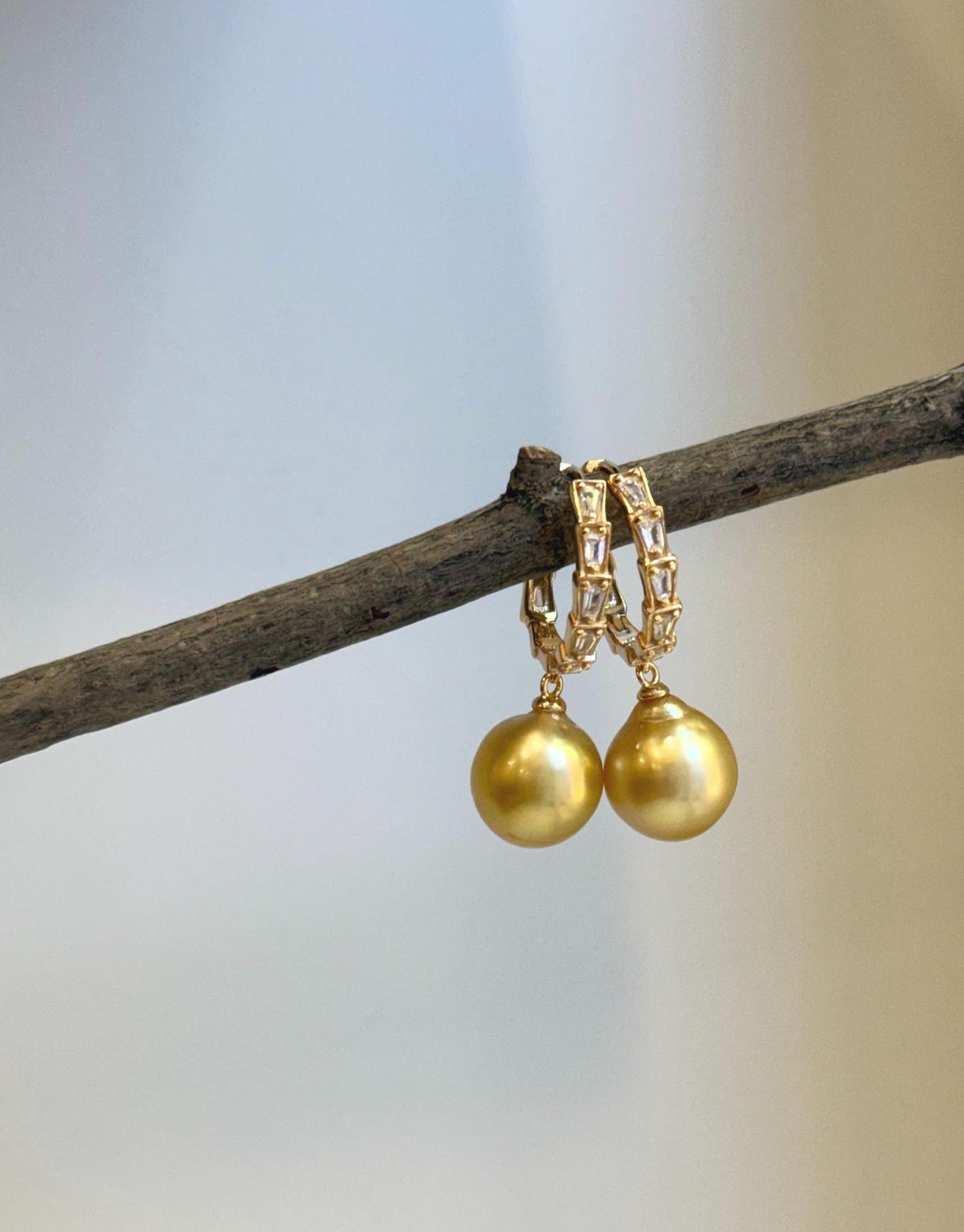 Crystal details add sparkle above the golden pearls on these statement hoop earrings.