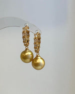 Gold-tone hoops frame luminous South Sea pearls for a classic evening look.