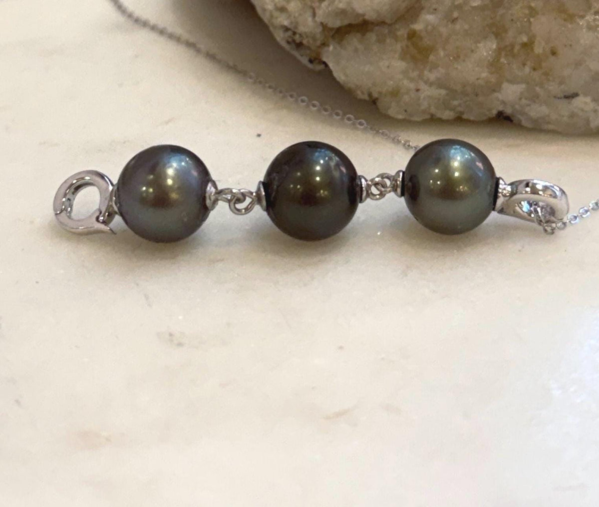 Three genuine Tahitian saltwater pearls in platinum and hunter tones with strong metallic shine.
