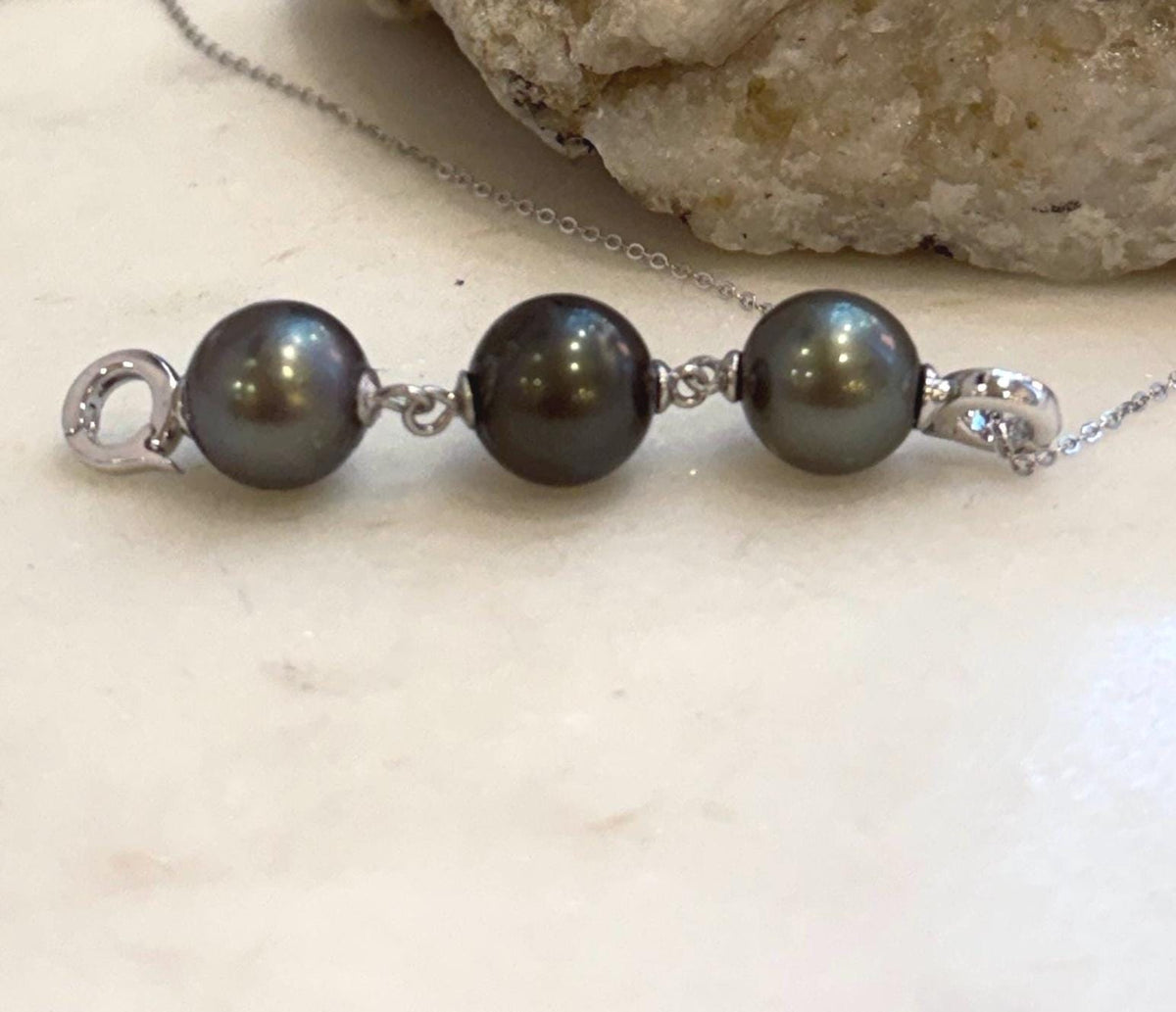 Three natural Tahitian ocean pearls showing rich platinum and deep hunter green overtones.