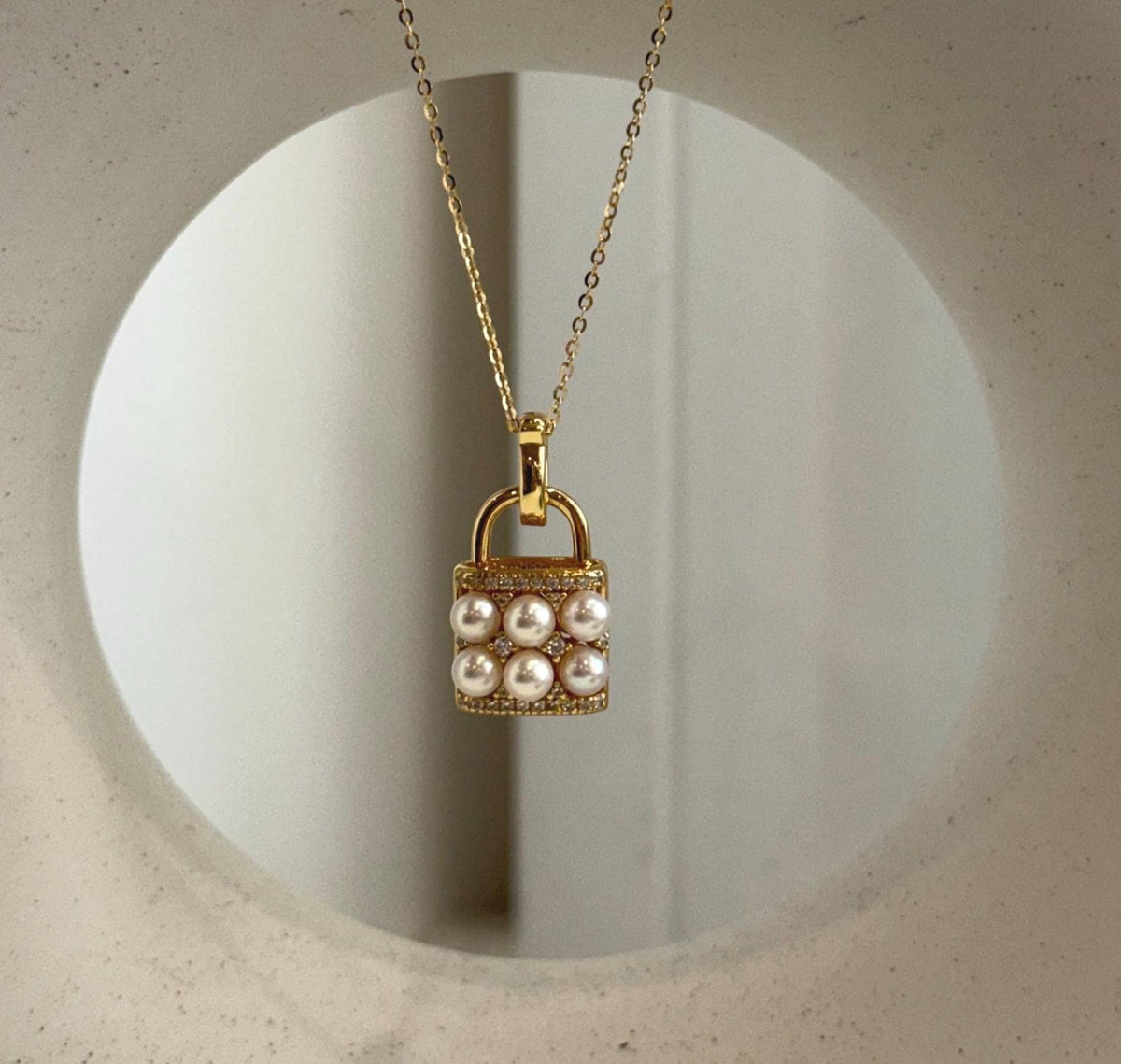 Handbag pendant necklace with six ivory Akoya pearls and a crystal-accented gold-tone setting
