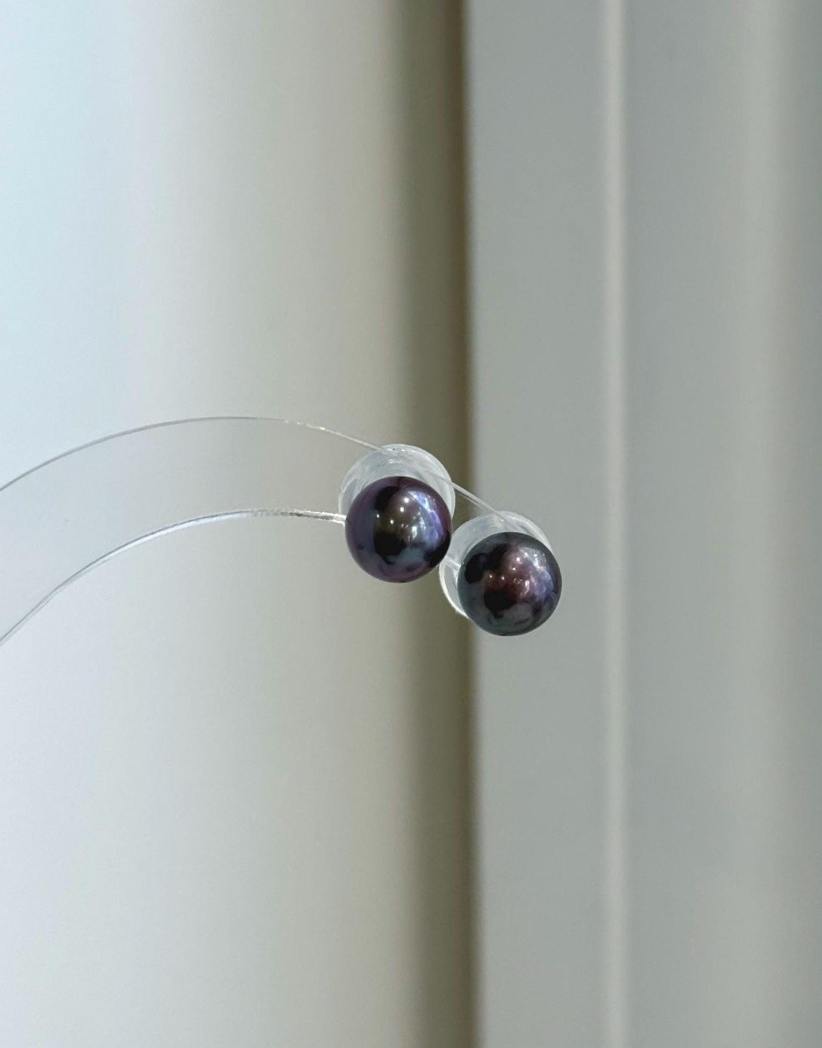 Deep plum pearl earrings with a glossy, reflective surface.