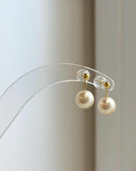 Elegant Akoya pearl earrings displayed on clear jewelry stand