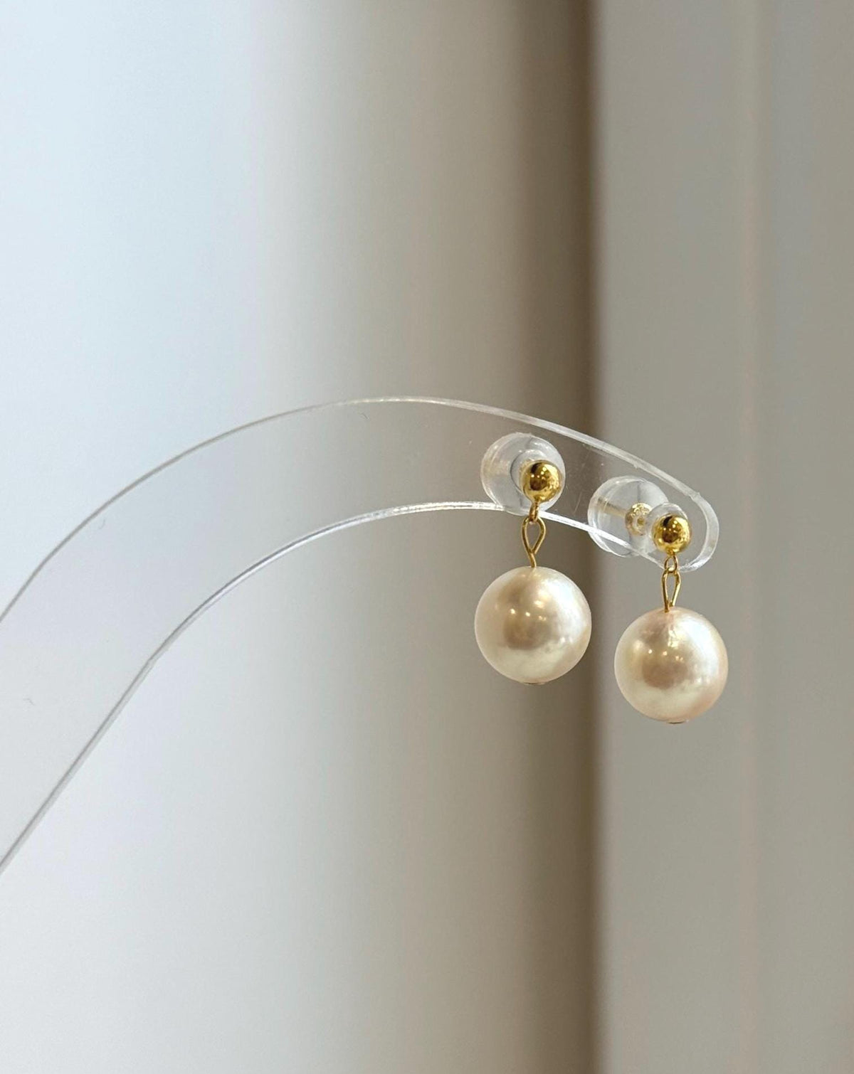 Elegant Akoya pearl earrings displayed on clear jewelry stand