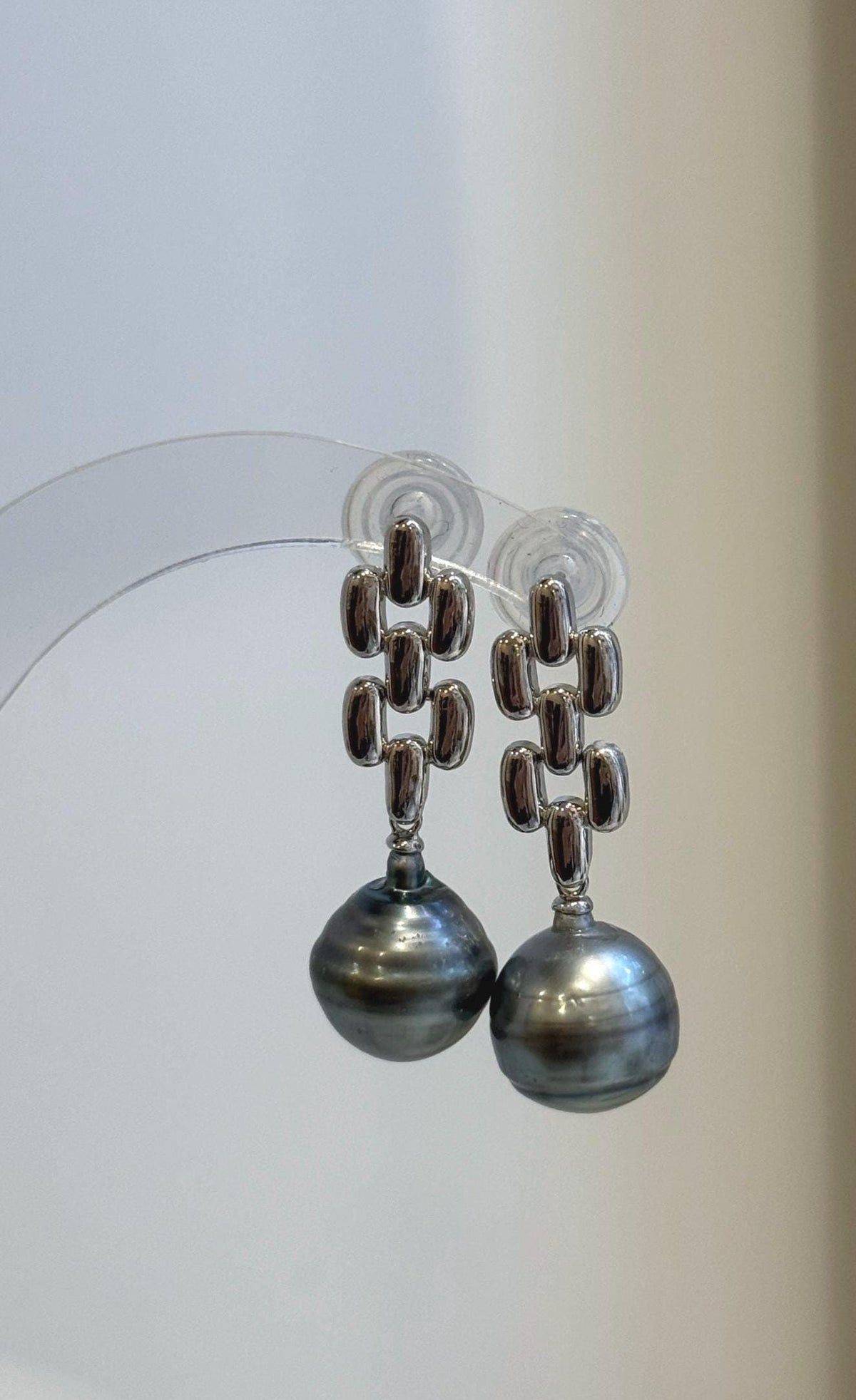 Pair of saltwater pearl earrings combining modern silver shapes with soft platinum color.