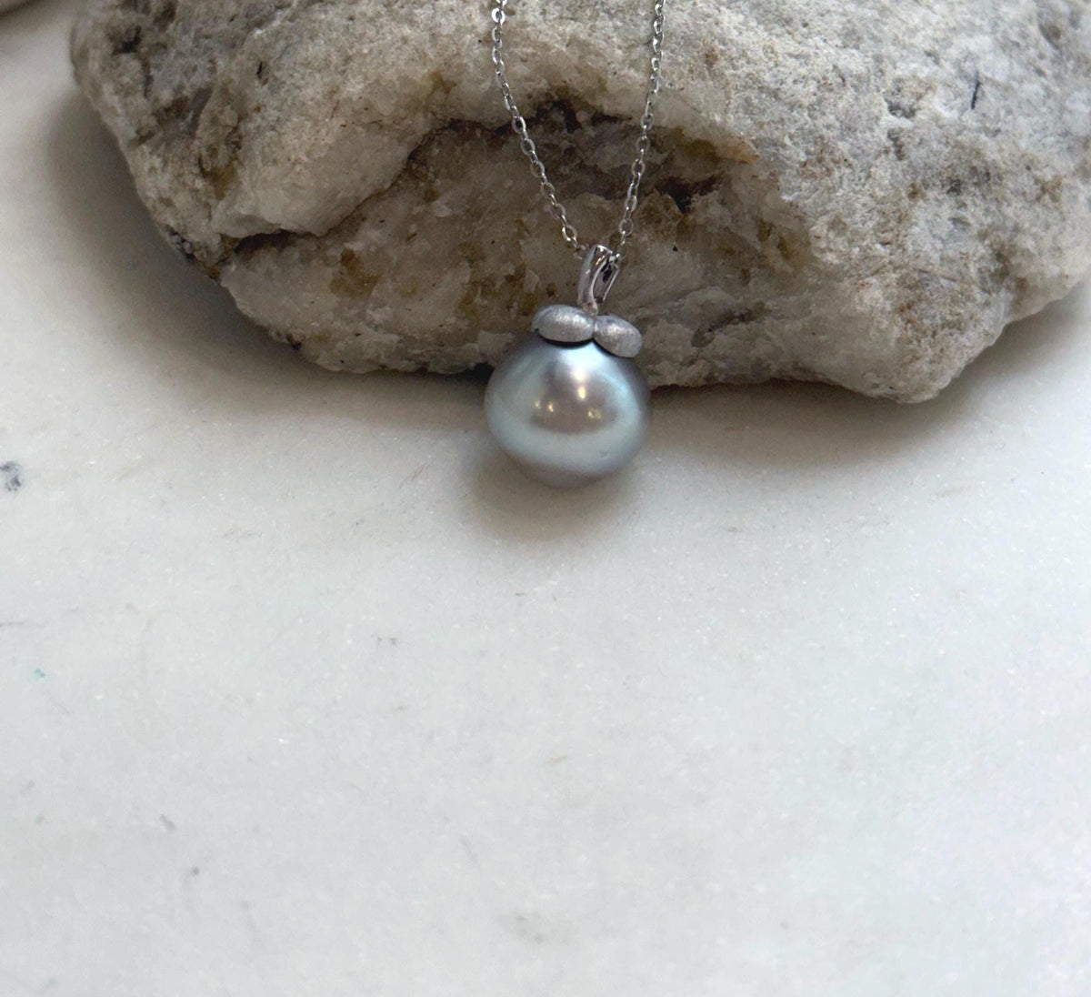 Persimmon-inspired sterling silver details above the silver taupe pearl.