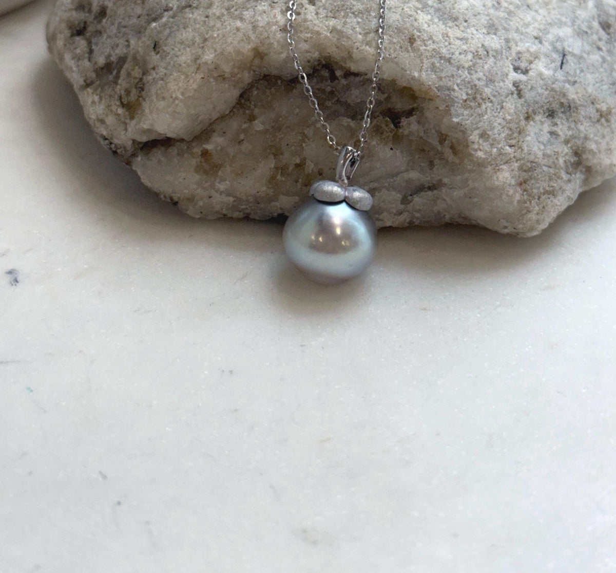Detailed view of the pearl’s luster and persimmon-shaped pendant setting.