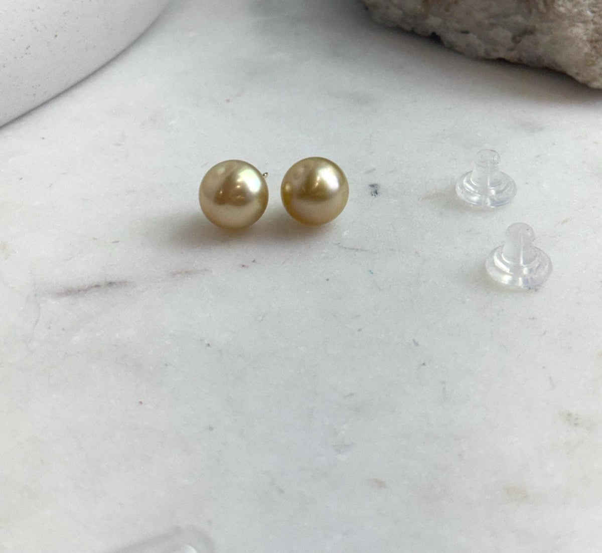 Minimalist golden pearl stud earrings in sterling silver.