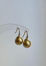 High heel sterling silver hooks holding golden saltwater pearls.