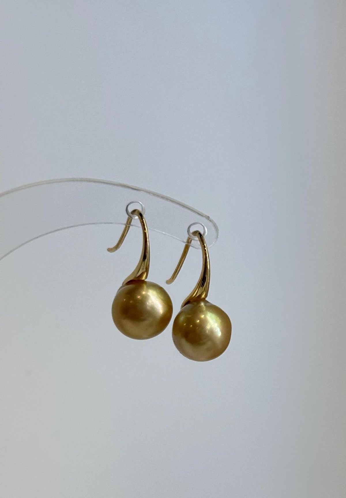 High heel sterling silver hooks holding golden saltwater pearls.