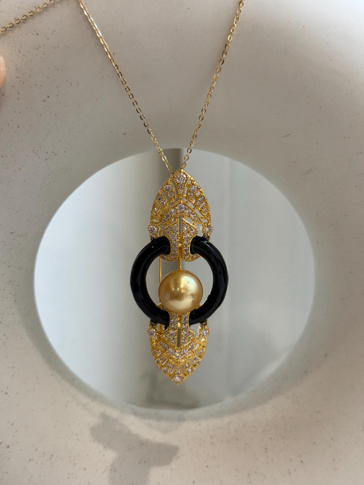 Convertible South Sea pearl brooch pendant with intricate openwork and clear stone accents.