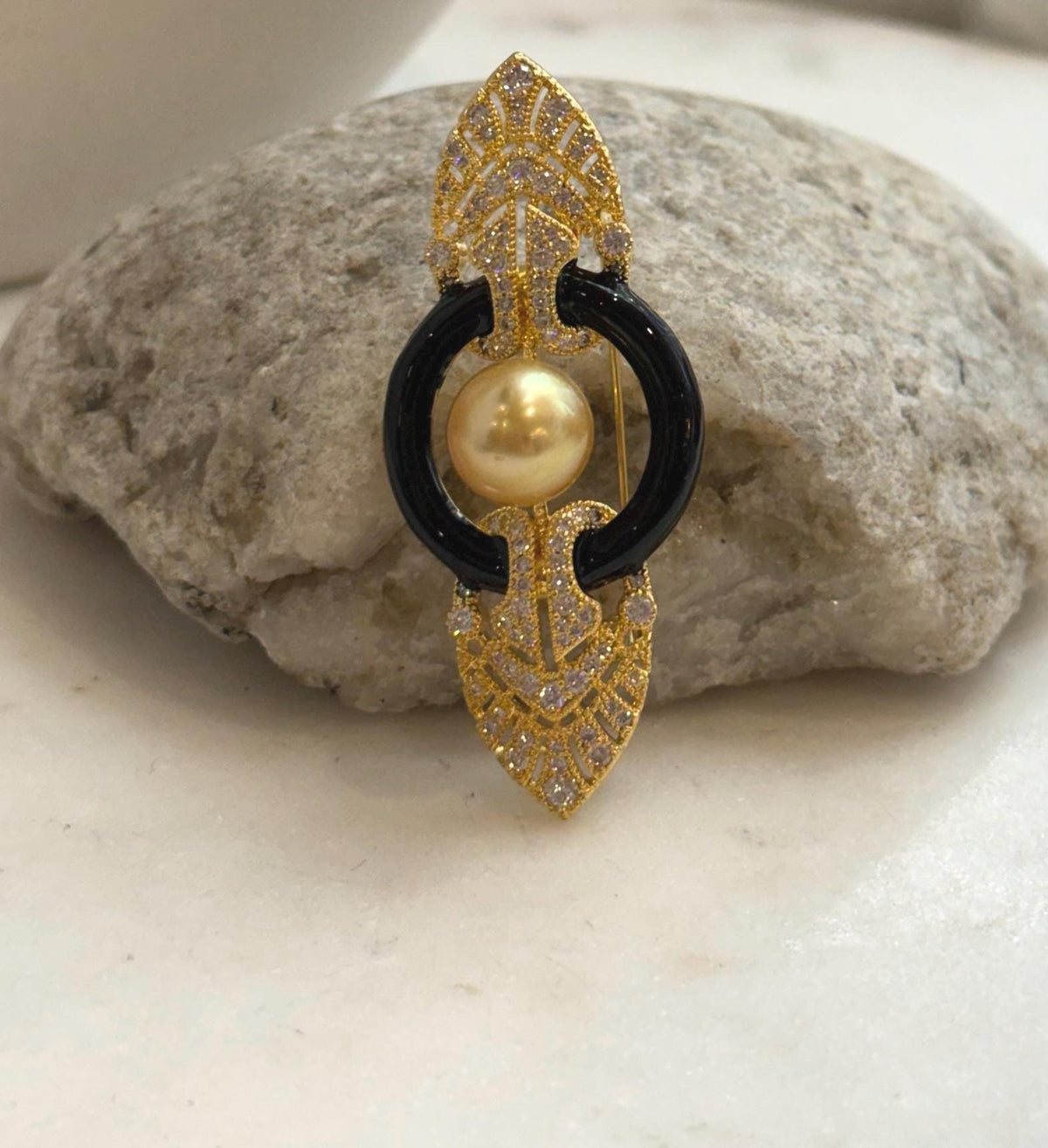 South Sea golden pearl brooch pendant with glossy black curved accents and ornate gold tone details.