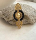 Golden South Sea pearl framed by two glossy black arcs between decorative gold tone pointed ends.