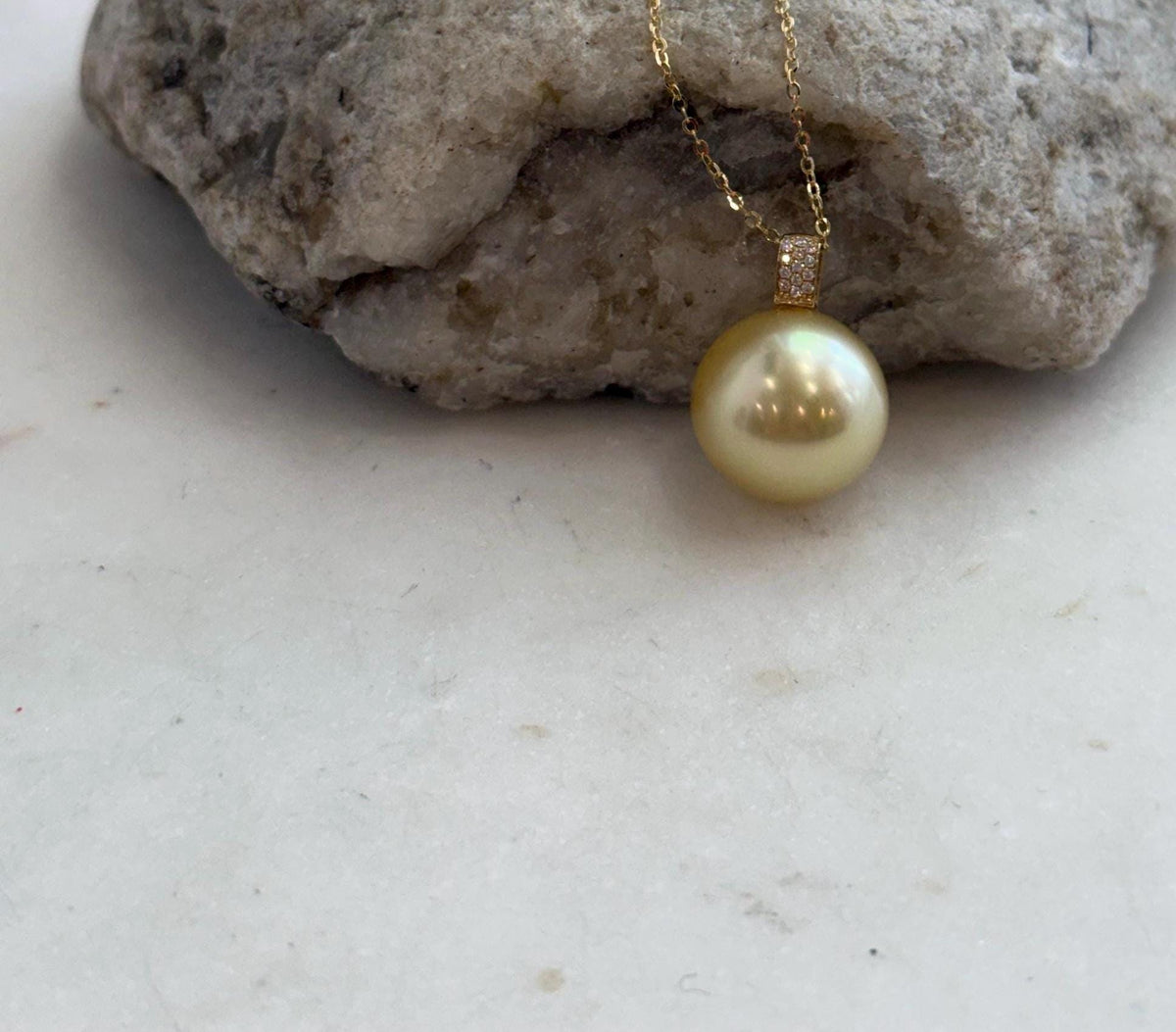 Golden pearl pendant with a sparkling moissanite accent.