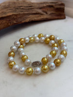 Front view of a two-tone freshwater pearl necklace styled in a soft curve.