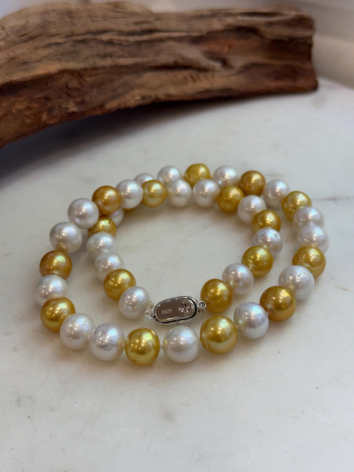 Front view of a two-tone freshwater pearl necklace styled in a soft curve.