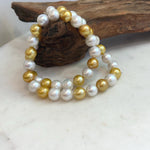 White Edison pearls displaying soft iridescence beside lustrous golden pearls.