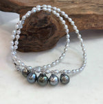White pearls and sterling silver spacer beads along the necklace strand.