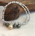 Five South Sea pearl drops with platinum and golden tones displayed on a necklace stand.
