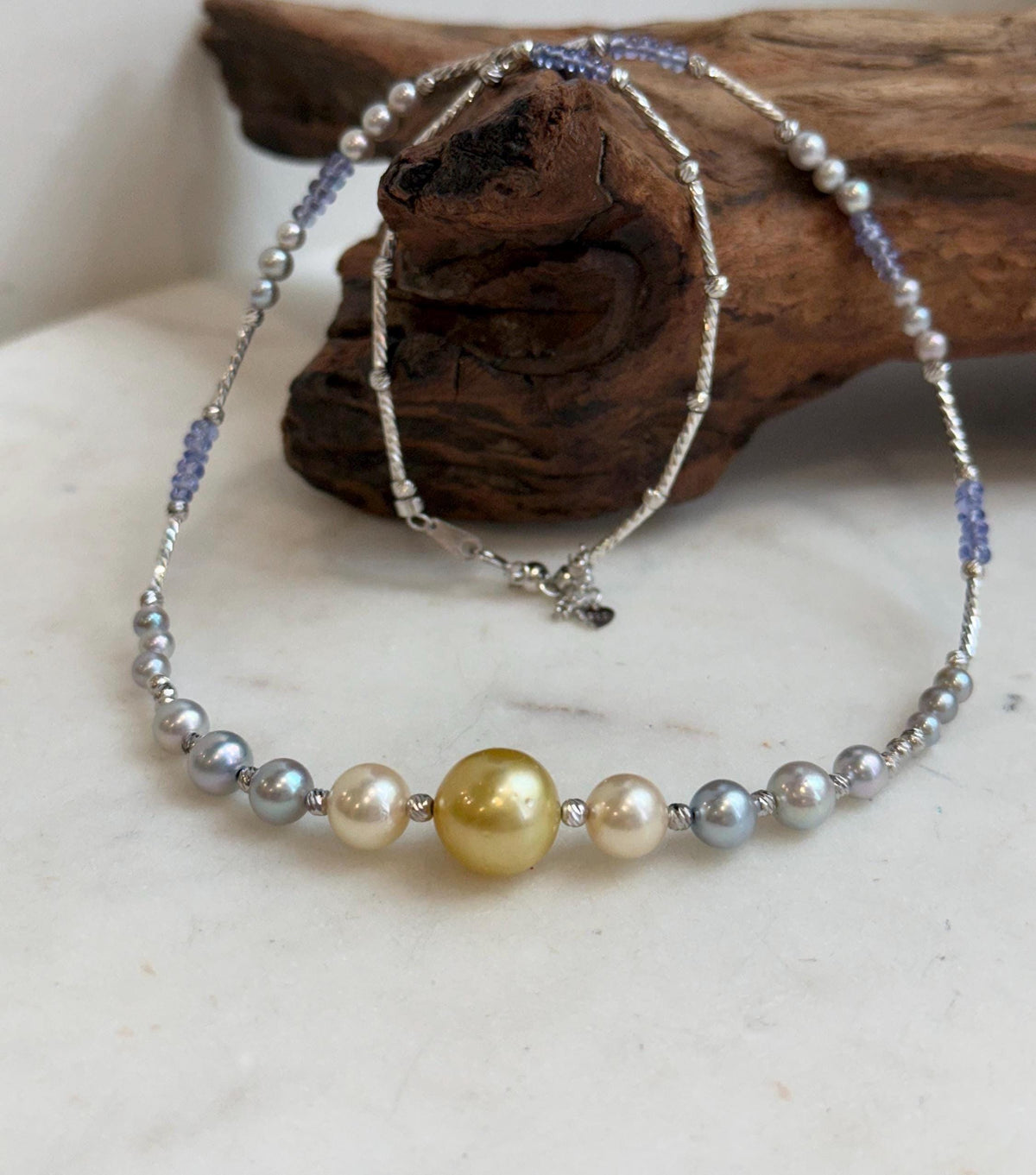 Golden pearl centerpiece with blue tanzanite and silver decorative details.