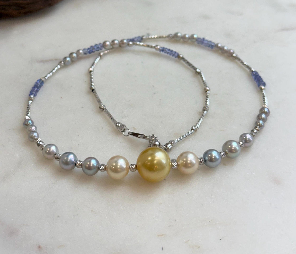 Saltwater pearl necklace with a golden center pearl and blue tanzanite beads.