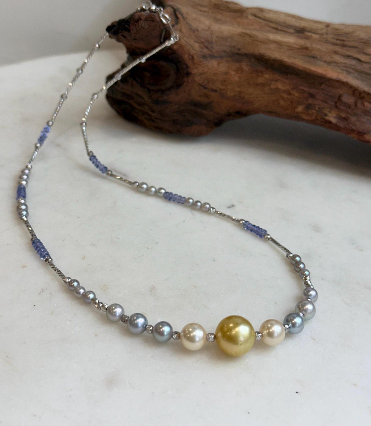 Saltwater pearl necklace with a golden center pearl and blue tanzanite beads.