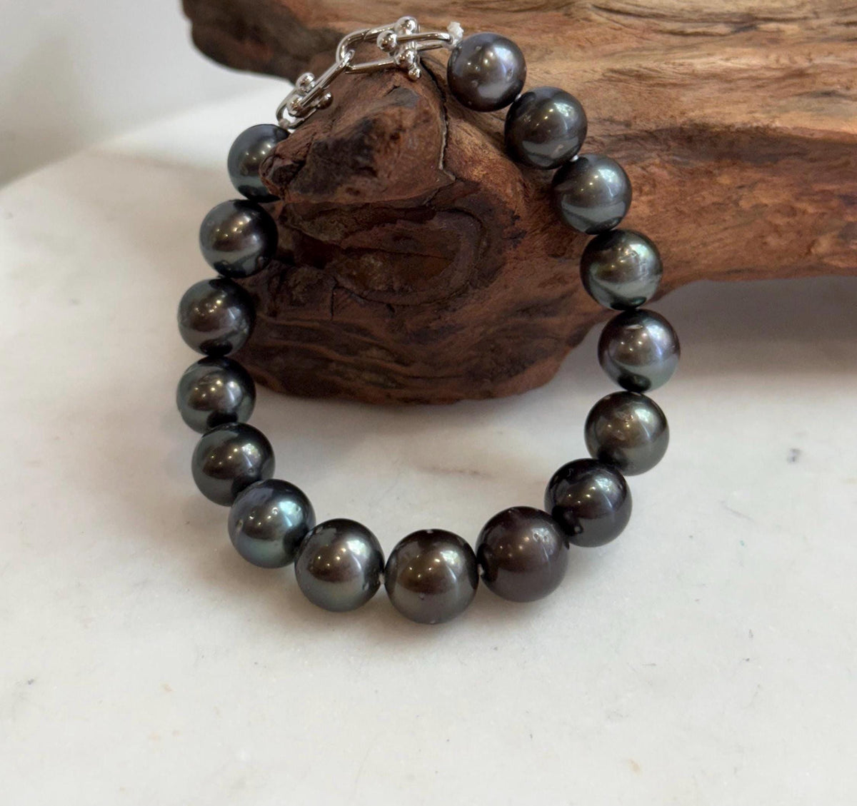 Sixteen-pearl bracelet with contrasting green and silver tones.