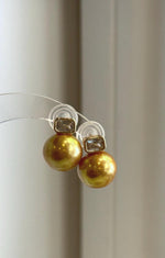 Minimalist stud earrings featuring large golden freshwater pearls.