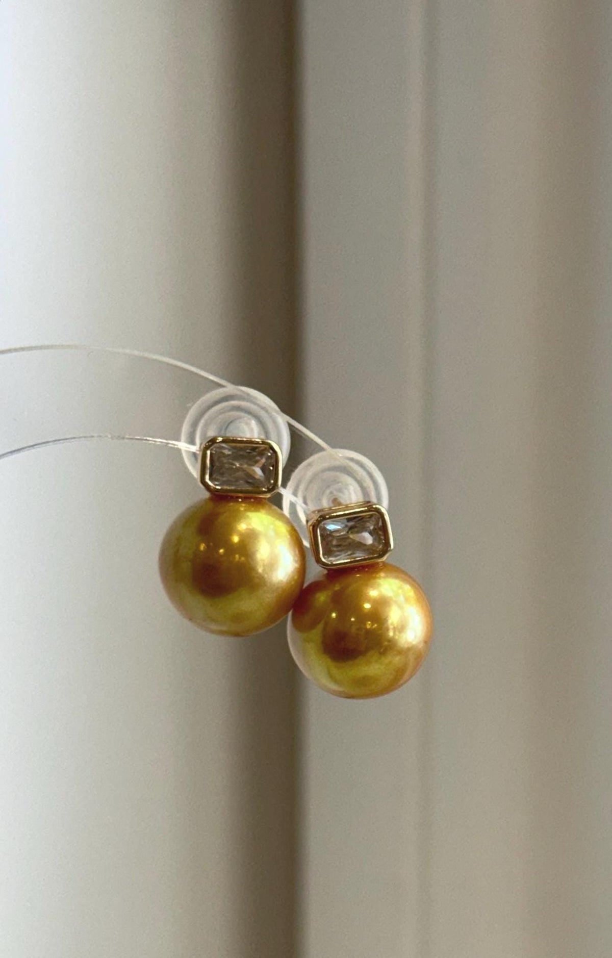 Minimalist stud earrings featuring large golden freshwater pearls.