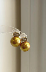 Side view of the minimalist golden pearl studs.