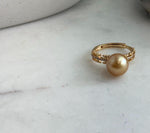 Adjustable pearl ring with a layered gold-tone band and sparkling accents.