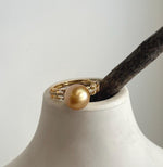 Side view of the golden pearl and decorative details along the ring band.
