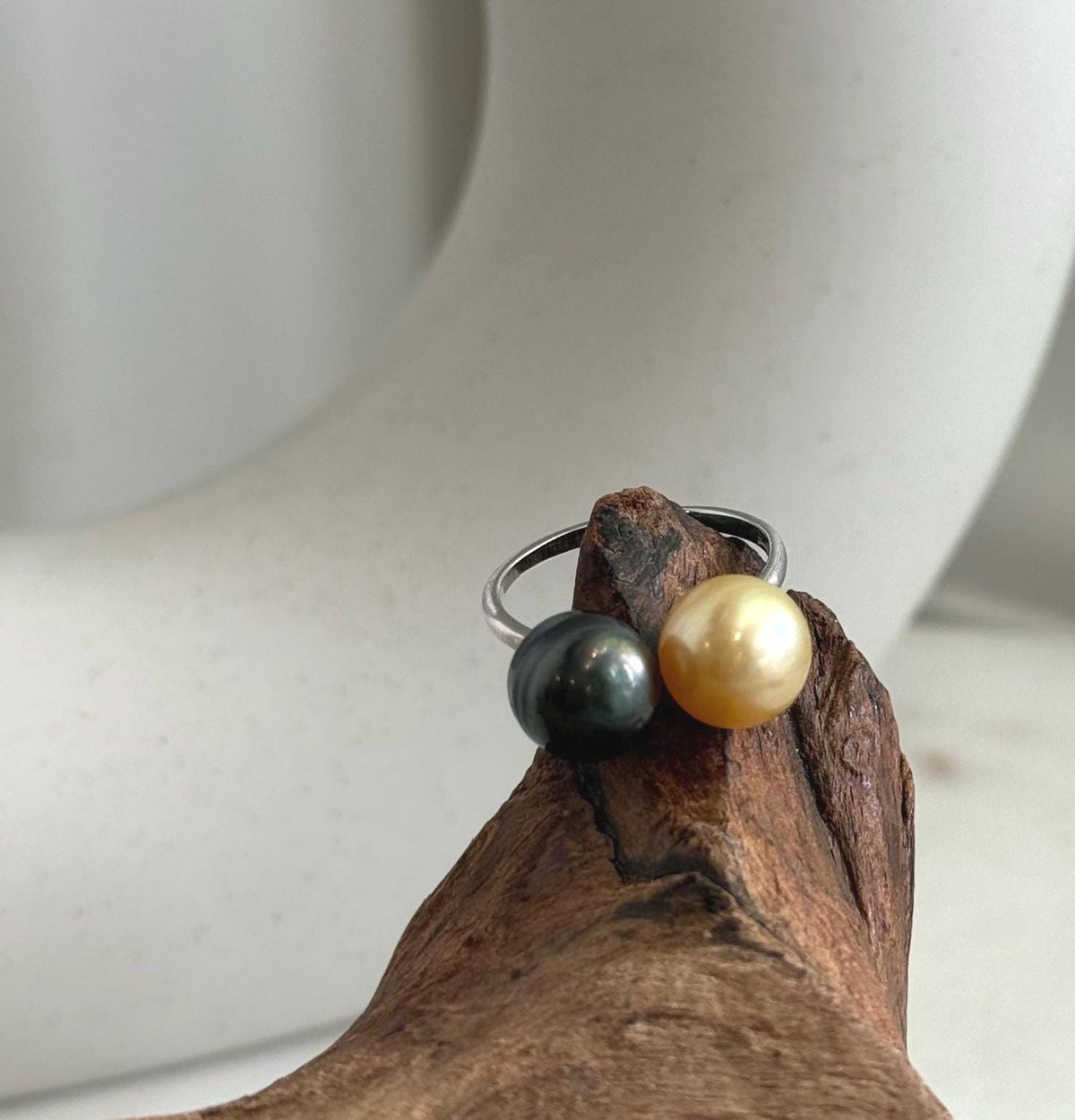 Dark Tahitian pearl with reflective luster beside a warm golden pearl.