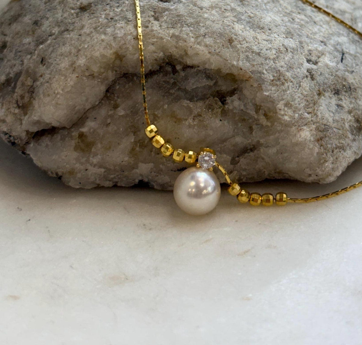 Genuine saltwater Akoya pearl necklace featuring an ivory pearl and gold-tone bead accents.