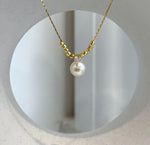Akoya pearl necklace with a soft ivory hue and gold-tone accents.