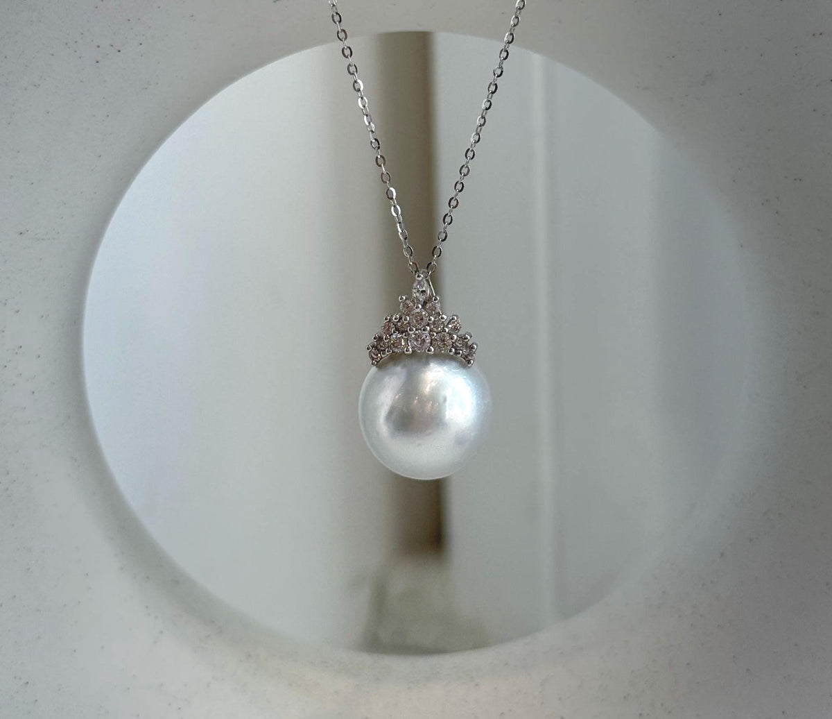 Round white pearl hanging beneath a decorative silver crown