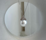 Round white pearl hanging beneath a decorative silver crown