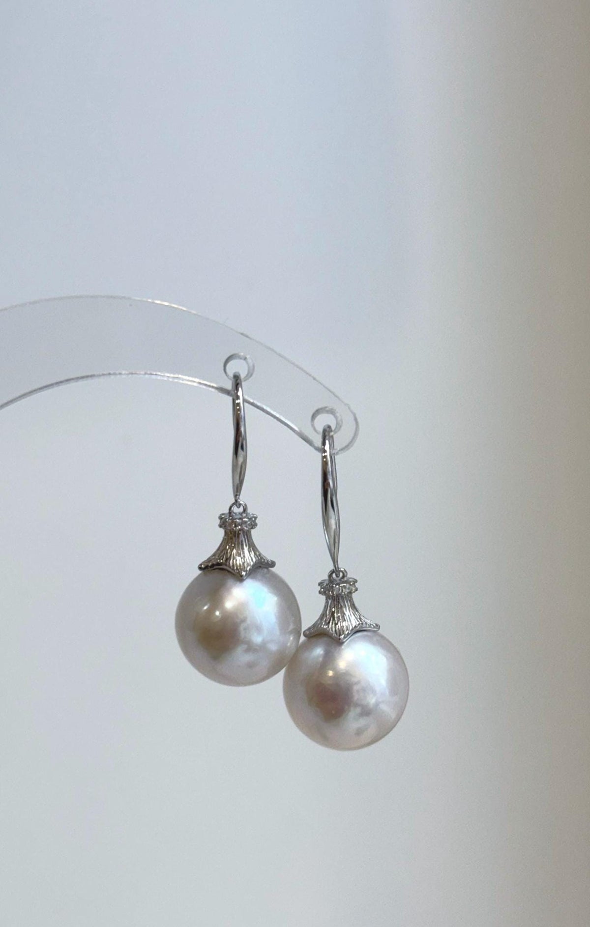 Lustrous freshwater pearl earrings with decorative silver flower-shaped caps.
