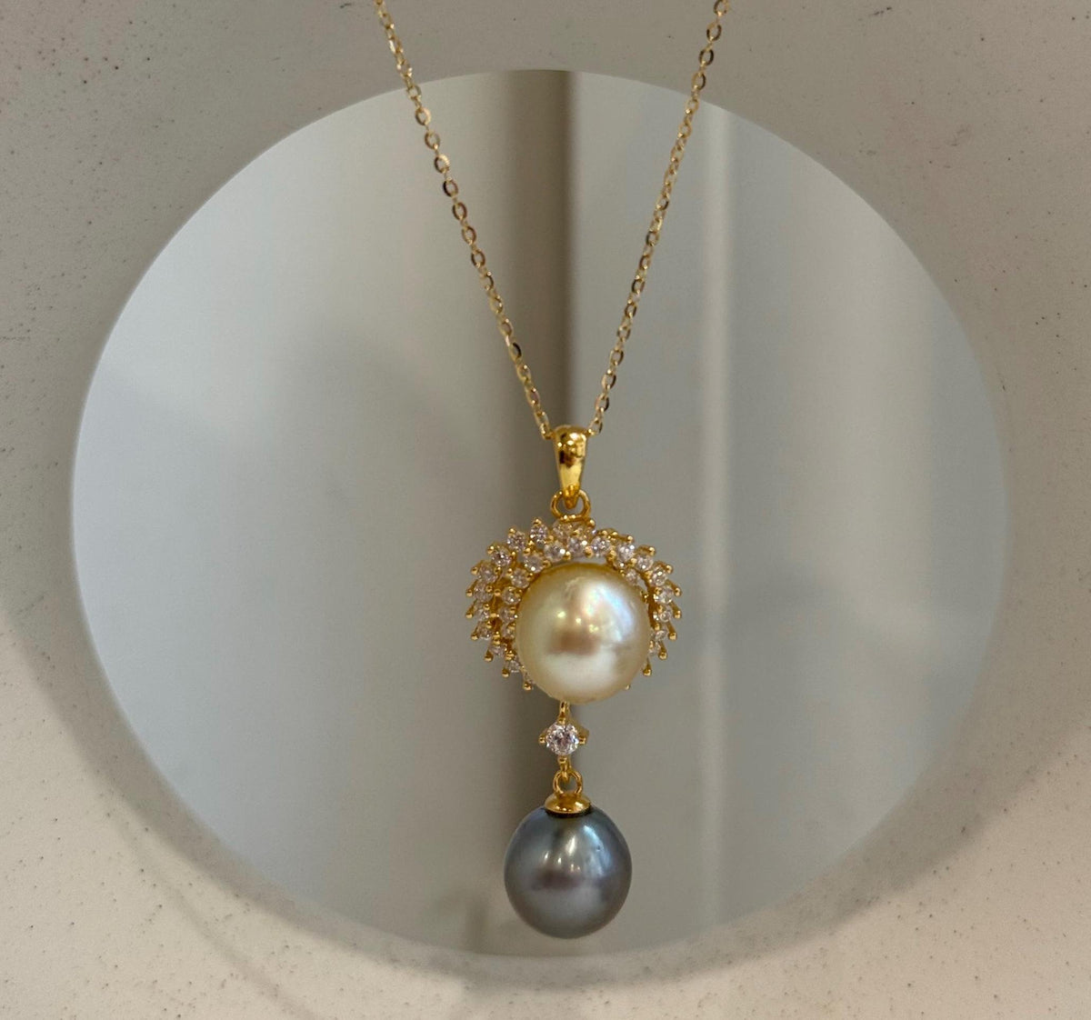 Two genuine saltwater pearls in a vertical pendant with gold-tone sterling silver details.